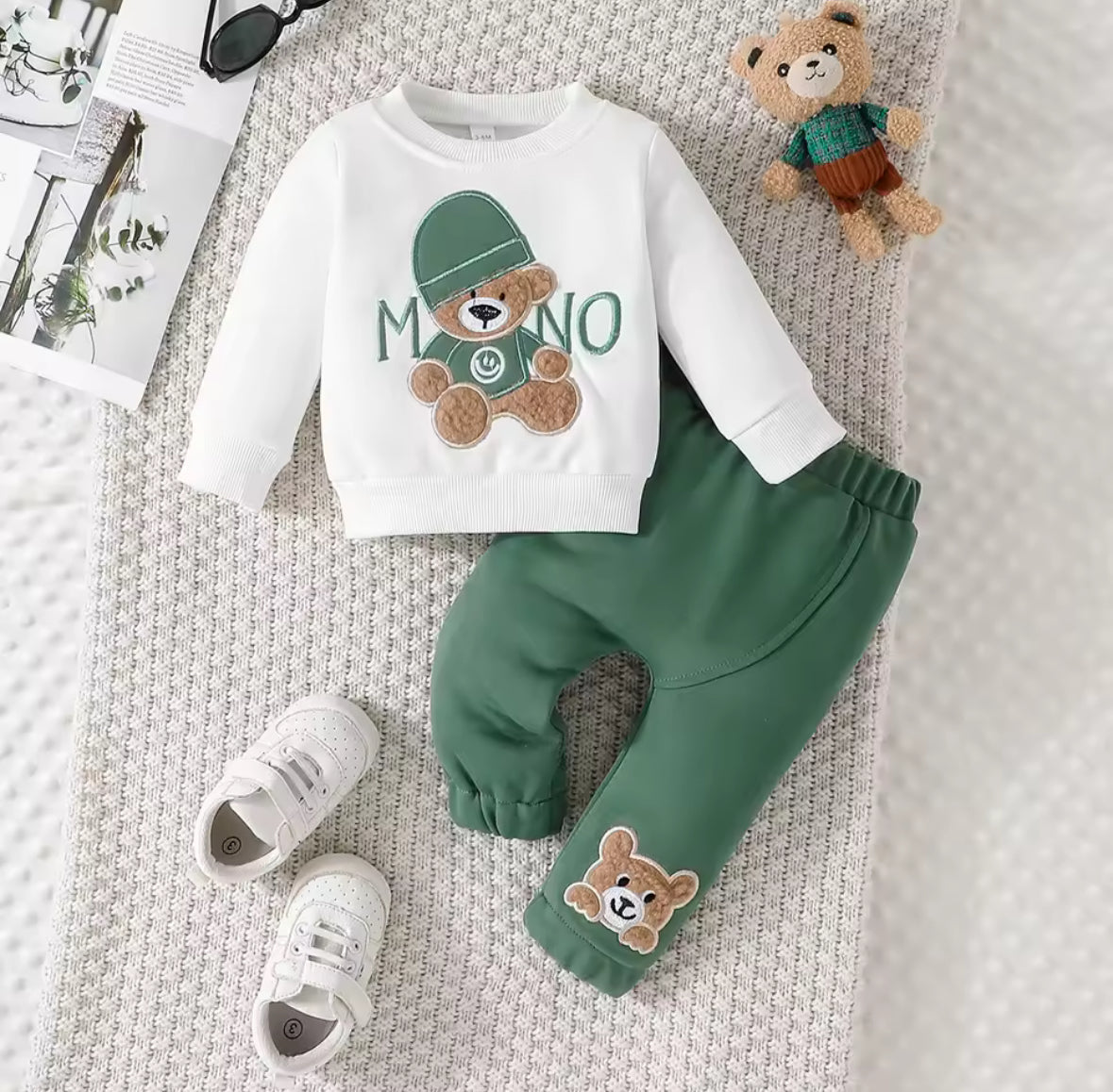 Children's outfit with white long-sleeve shirt and green pants featuring teddy bear designs on a textured surface.