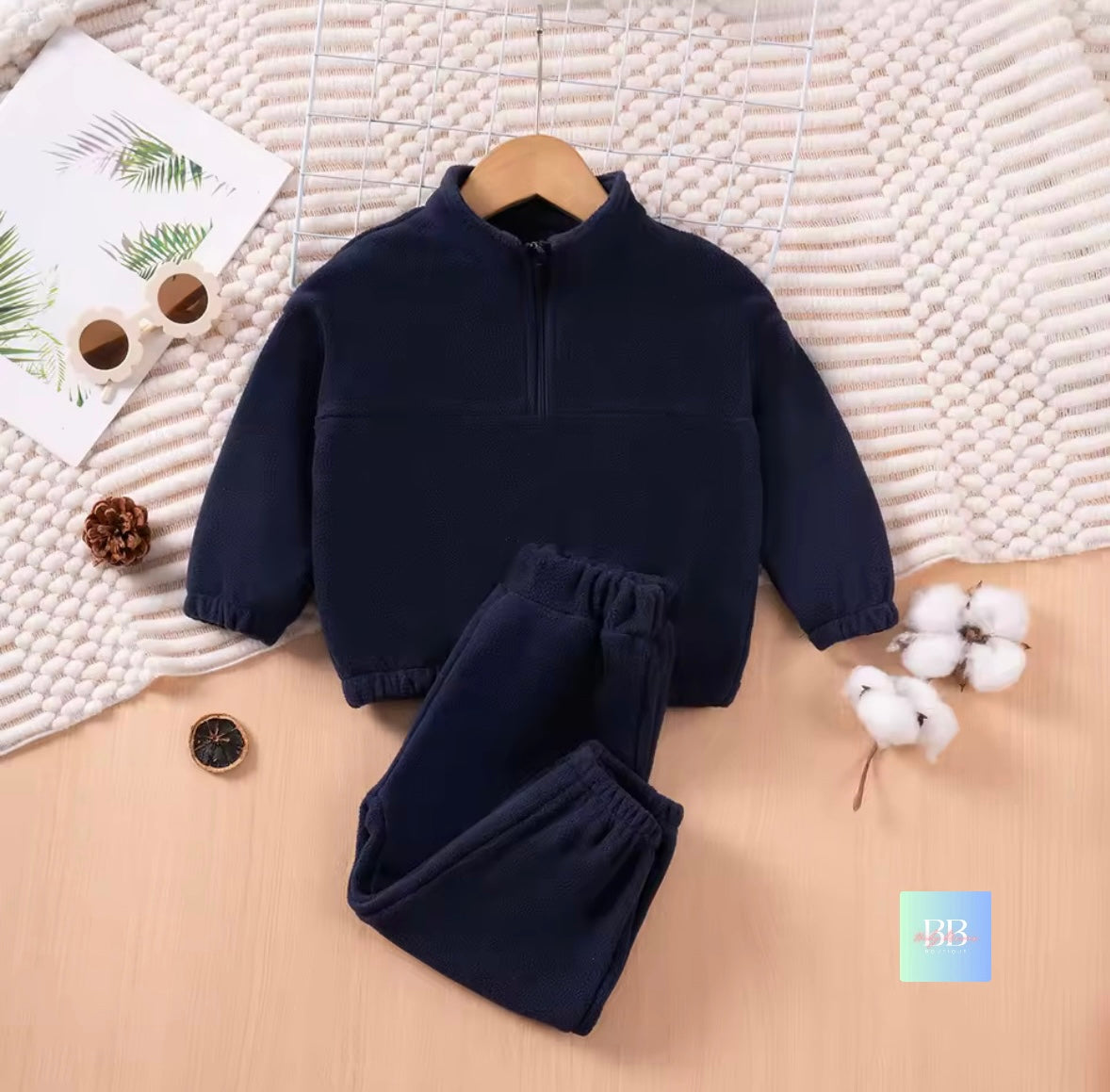 Navy blue children's outfit on a wooden surface with decorative items.