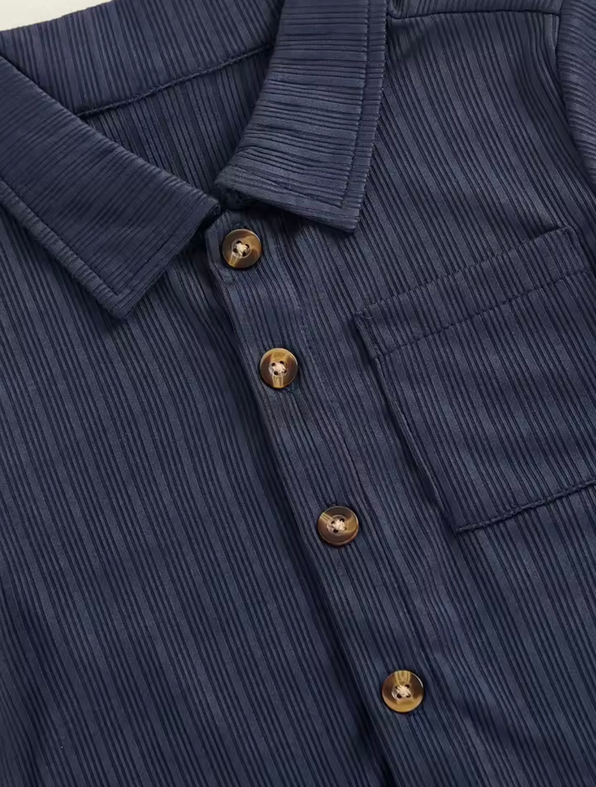 Close-up of a navy blue textured shirt with gold buttons