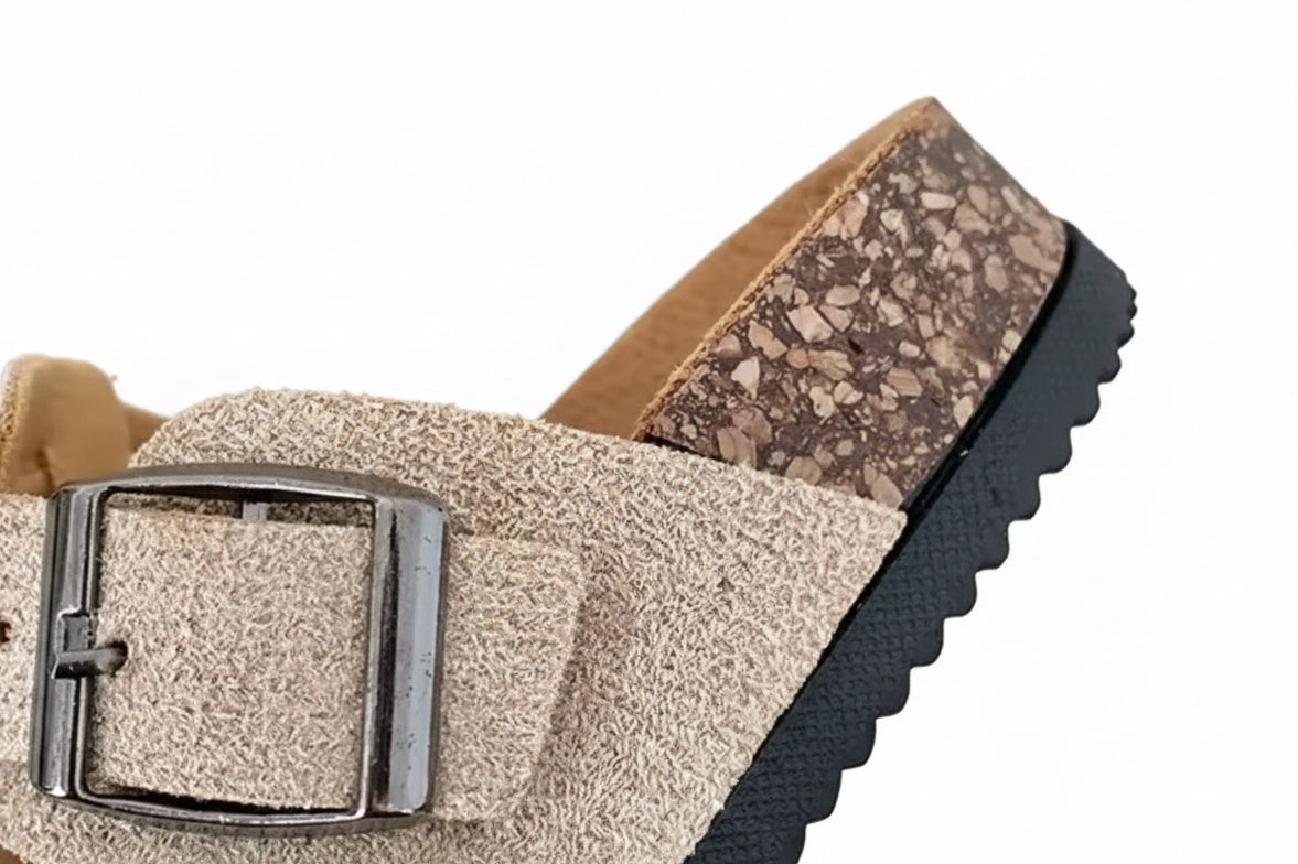 Close-up of a sandal with a textured strap and buckle on a blurred background