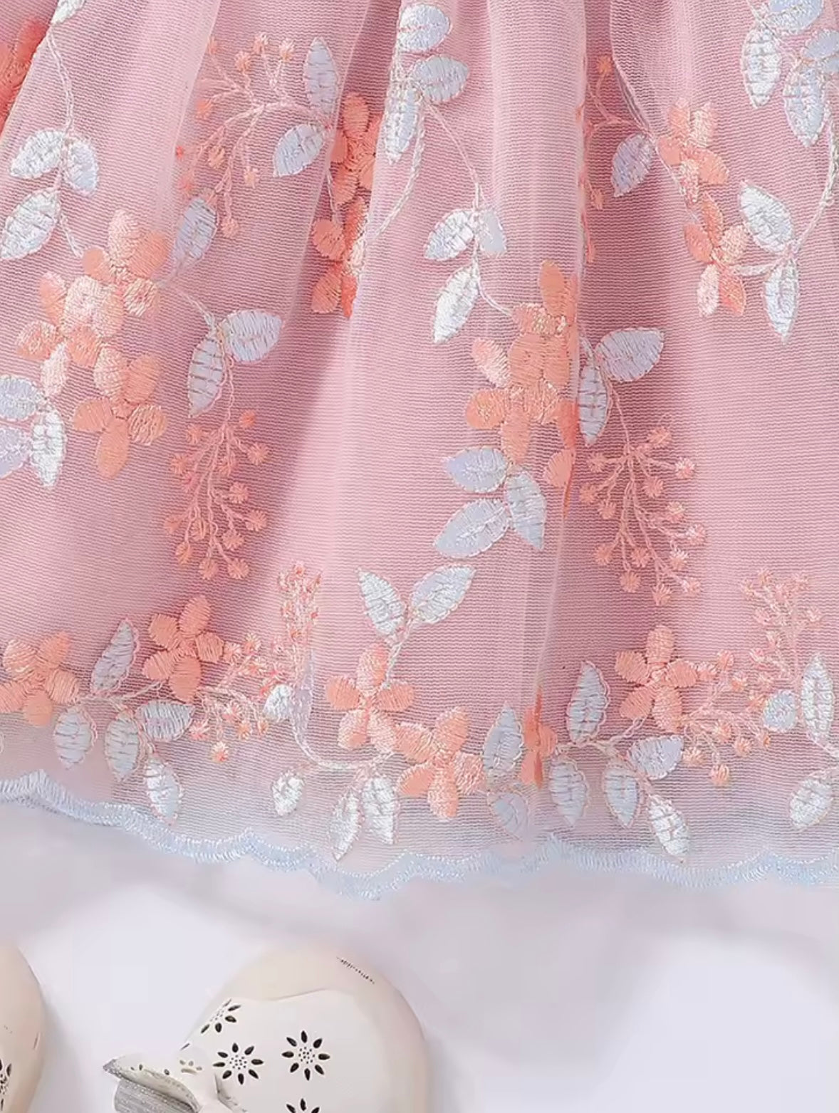 Close-up of a pink fabric with floral embroidery on a white background