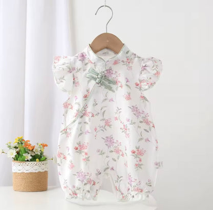Floral baby romper on a hanger against a white background