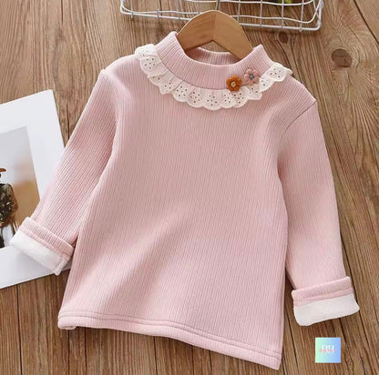 Pink ribbed sweater with lace collar on a wooden surface