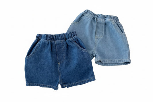 Two pairs of blue denim shorts on a white surface with a Mickey Mouse toy and a round plate in the background.