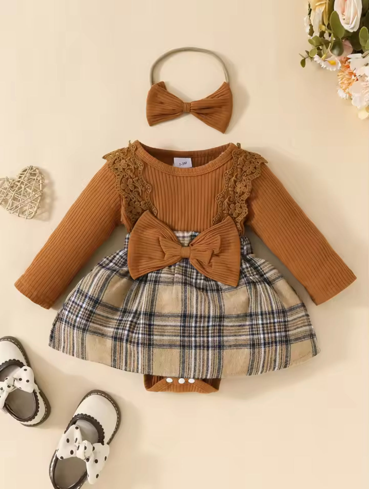 Children's outfit with brown top, plaid skirt, and matching headband on a beige background.