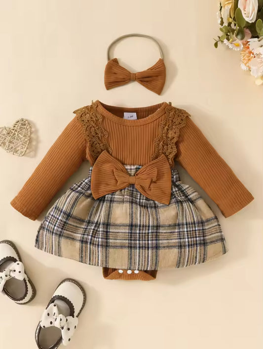 Children's outfit with brown top, plaid skirt, and matching headband on a beige background.