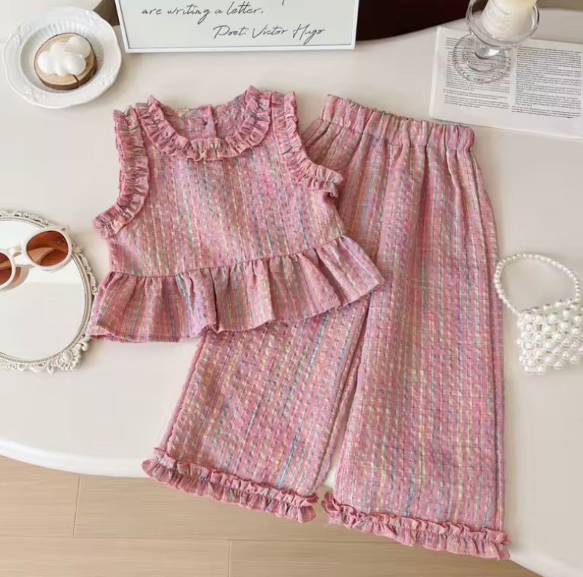 Pink ruffled outfit on a white surface with decorative items.