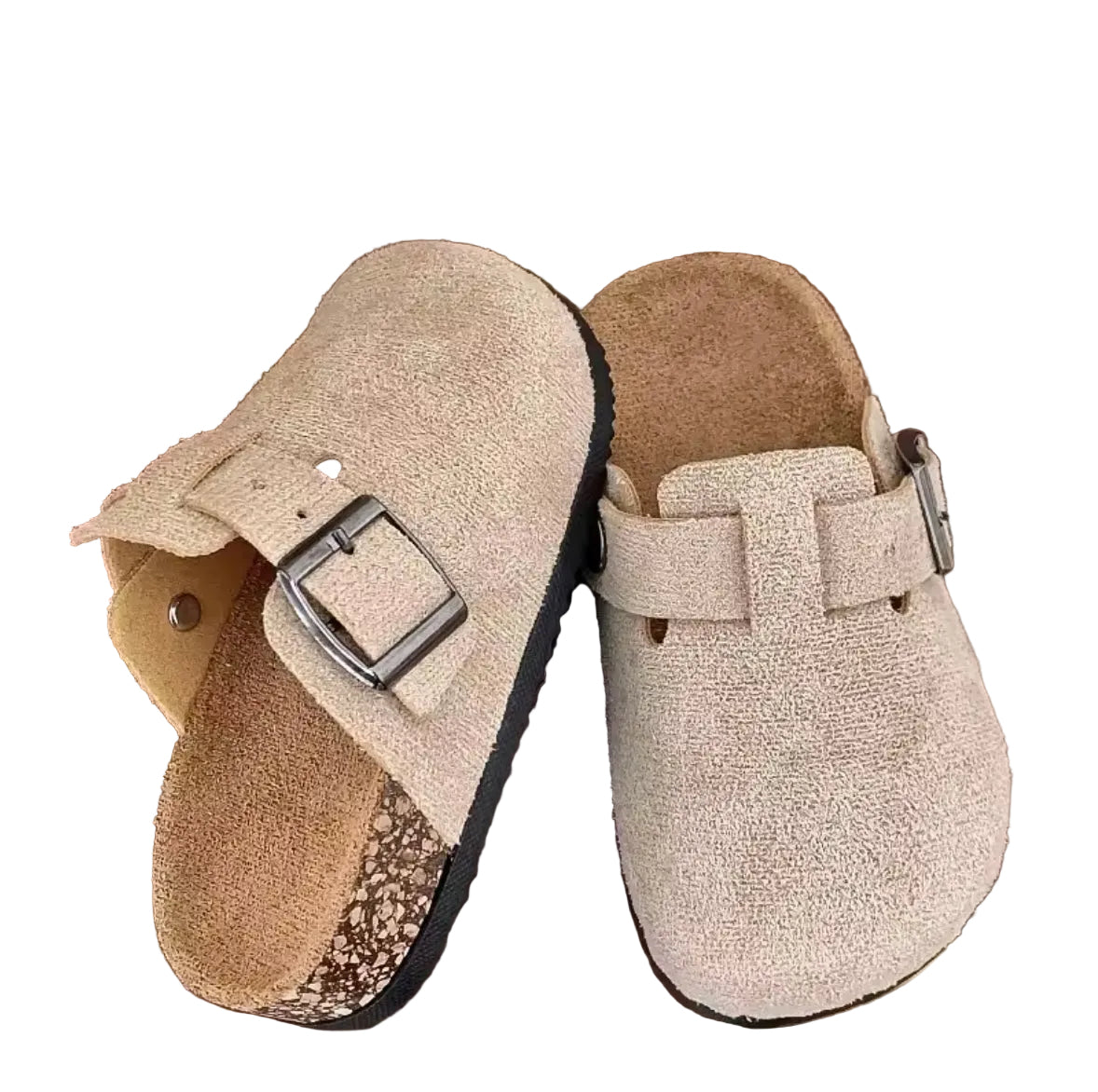 Pair of beige slippers with a buckle on a wooden surface.