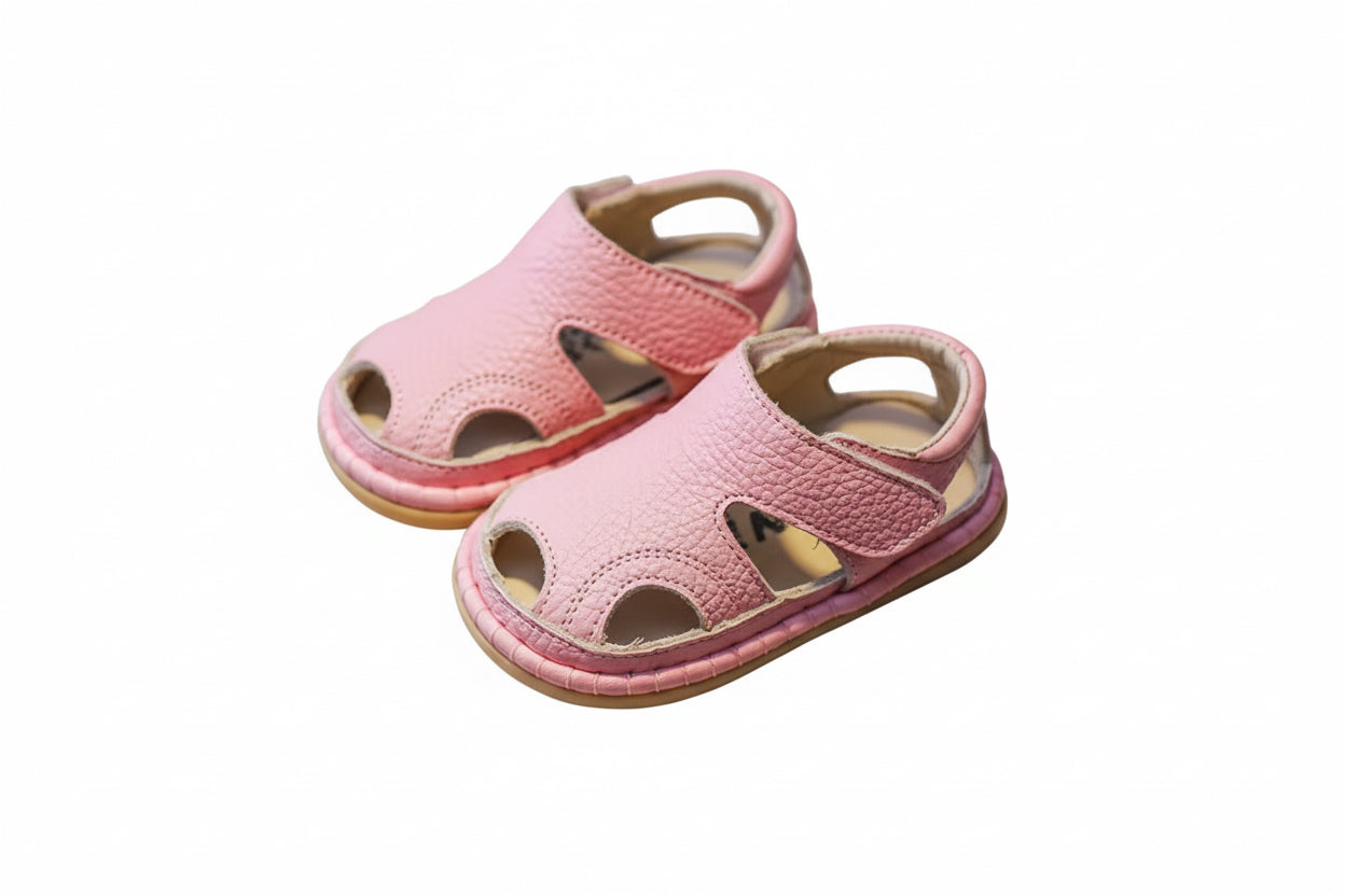 Pair of pink children's sandals on a brown surface