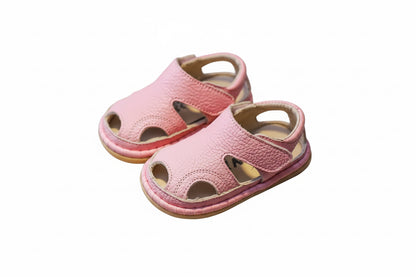 Pair of pink children's sandals on a brown surface