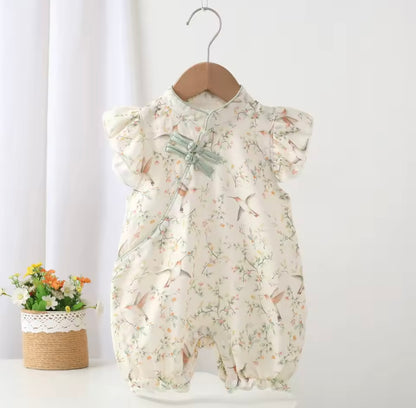 Floral baby romper on a hanger against a white background