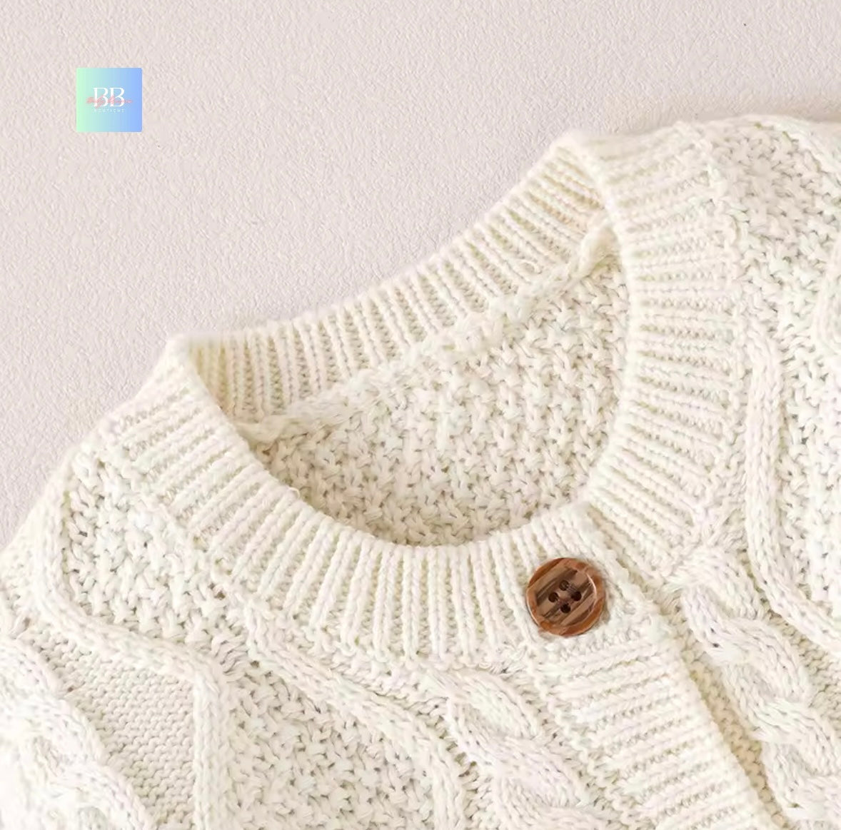Close-up of a white knitted cardigan with a brown button on a light gray background