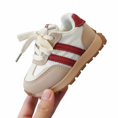 Child's sneaker with red stripes held in a hand against a blurred background