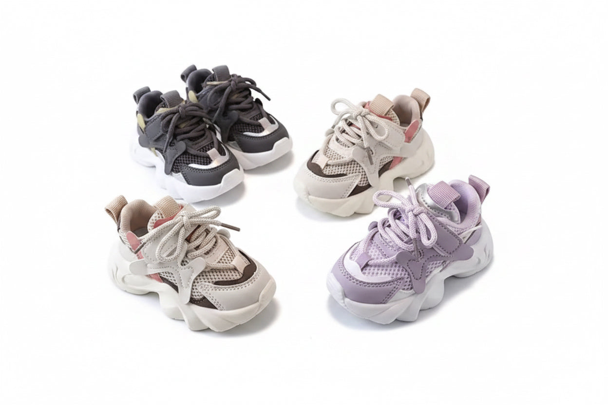 Four children's sneakers on a round gray table with a white container labeled 'XISHAN 731' in the background.