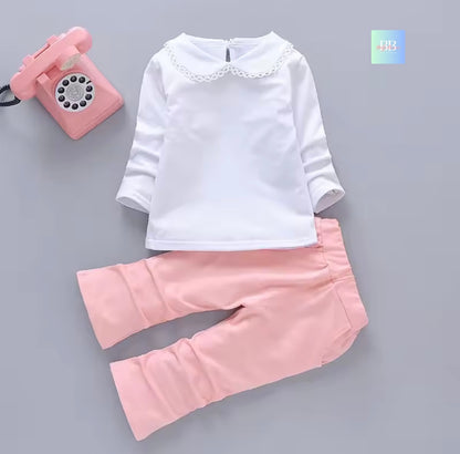White long-sleeve shirt and pink pants on a gray background with a pink toy phone.