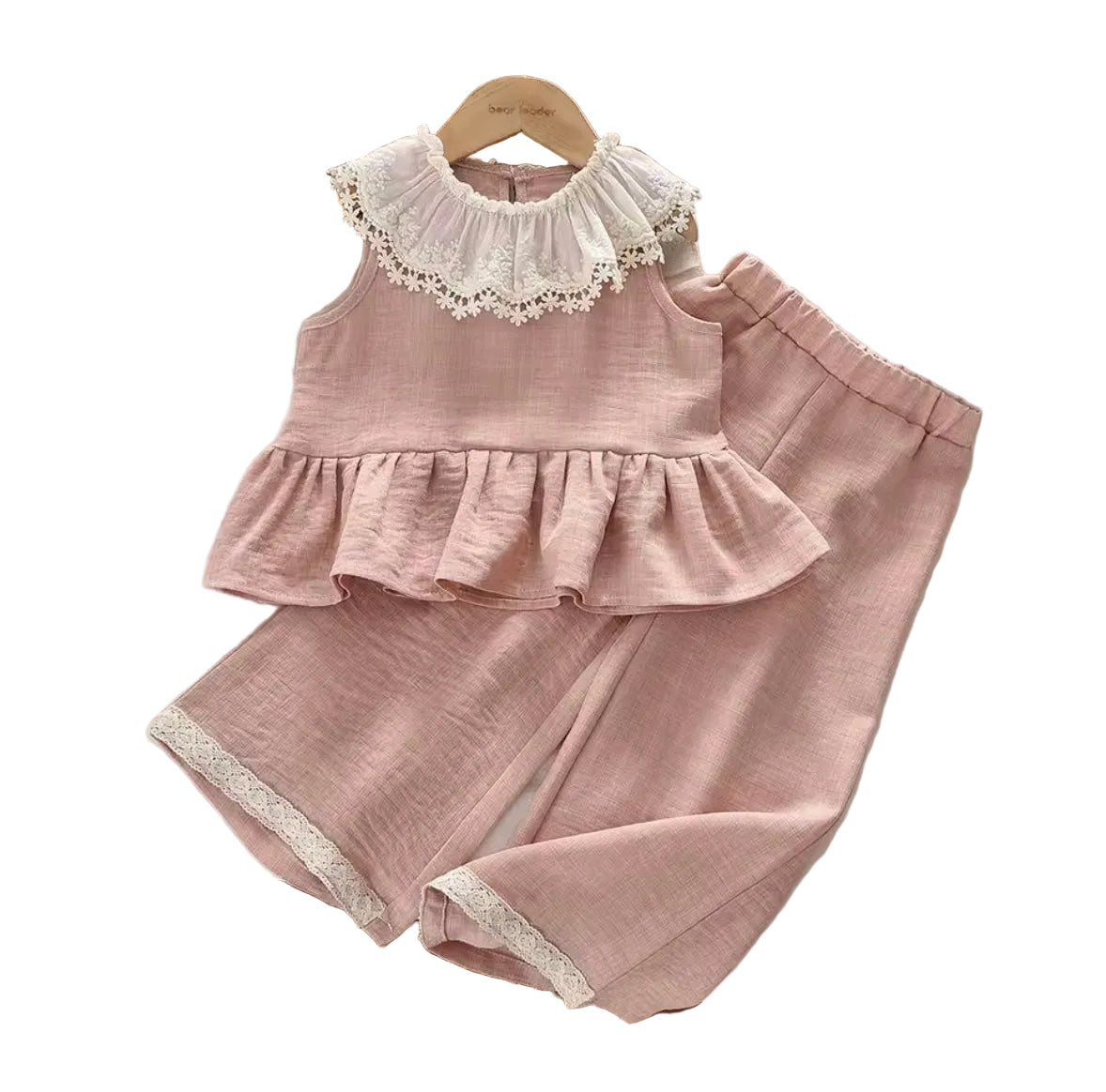 Pink children's outfit with lace details on a white surface