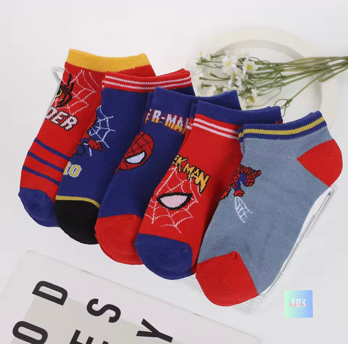 Set of Spider-Man themed socks on a white background with flowers.