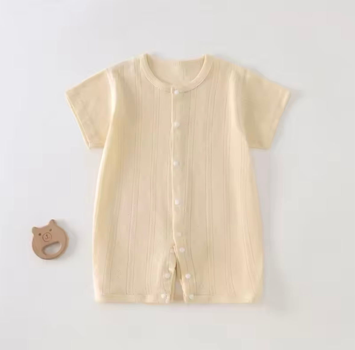 Beige baby romper with buttons on a light gray background