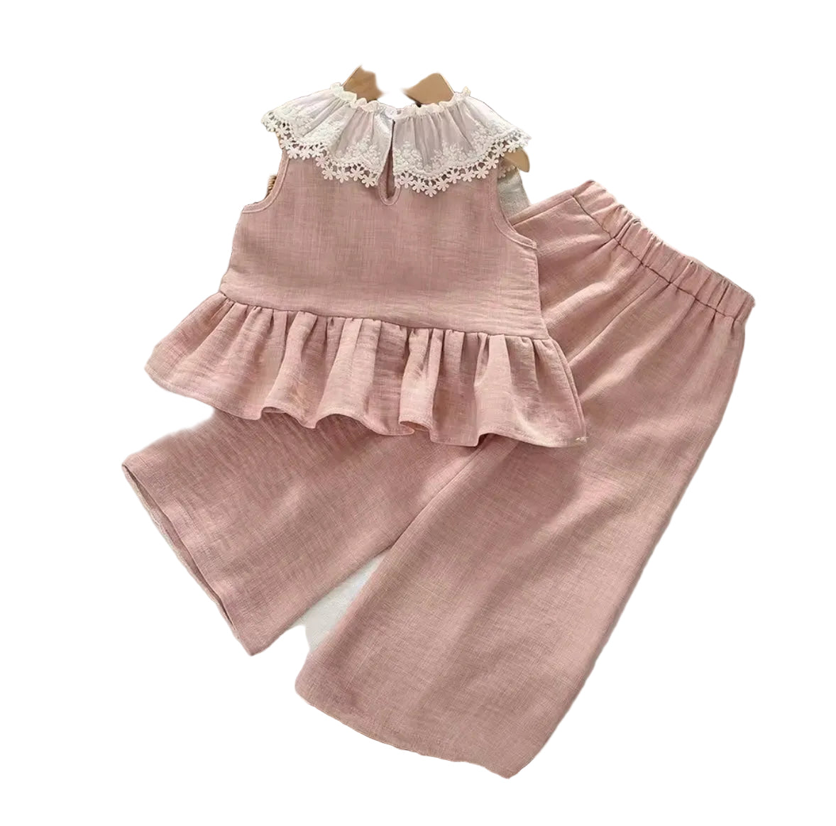 Pink children's outfit with lace details on a white surface