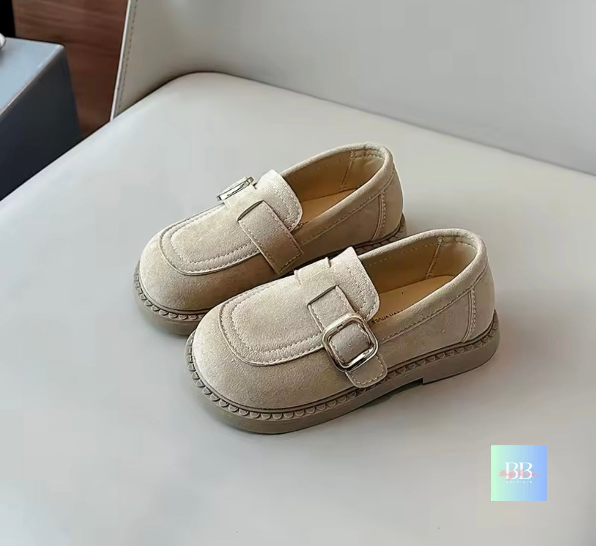 Pair of beige loafers with buckles on a light surface