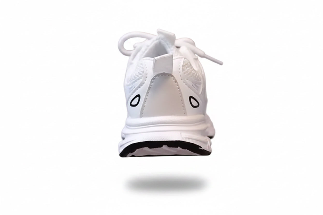 White sneaker with black accents held by a hand against a neutral background