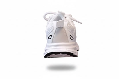 White sneaker with black accents held by a hand against a neutral background