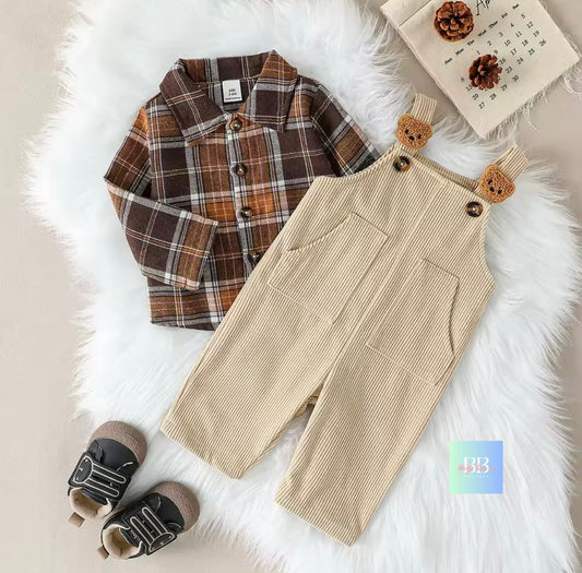 Children's plaid shirt and beige overalls with bear ears on a fluffy white surface.