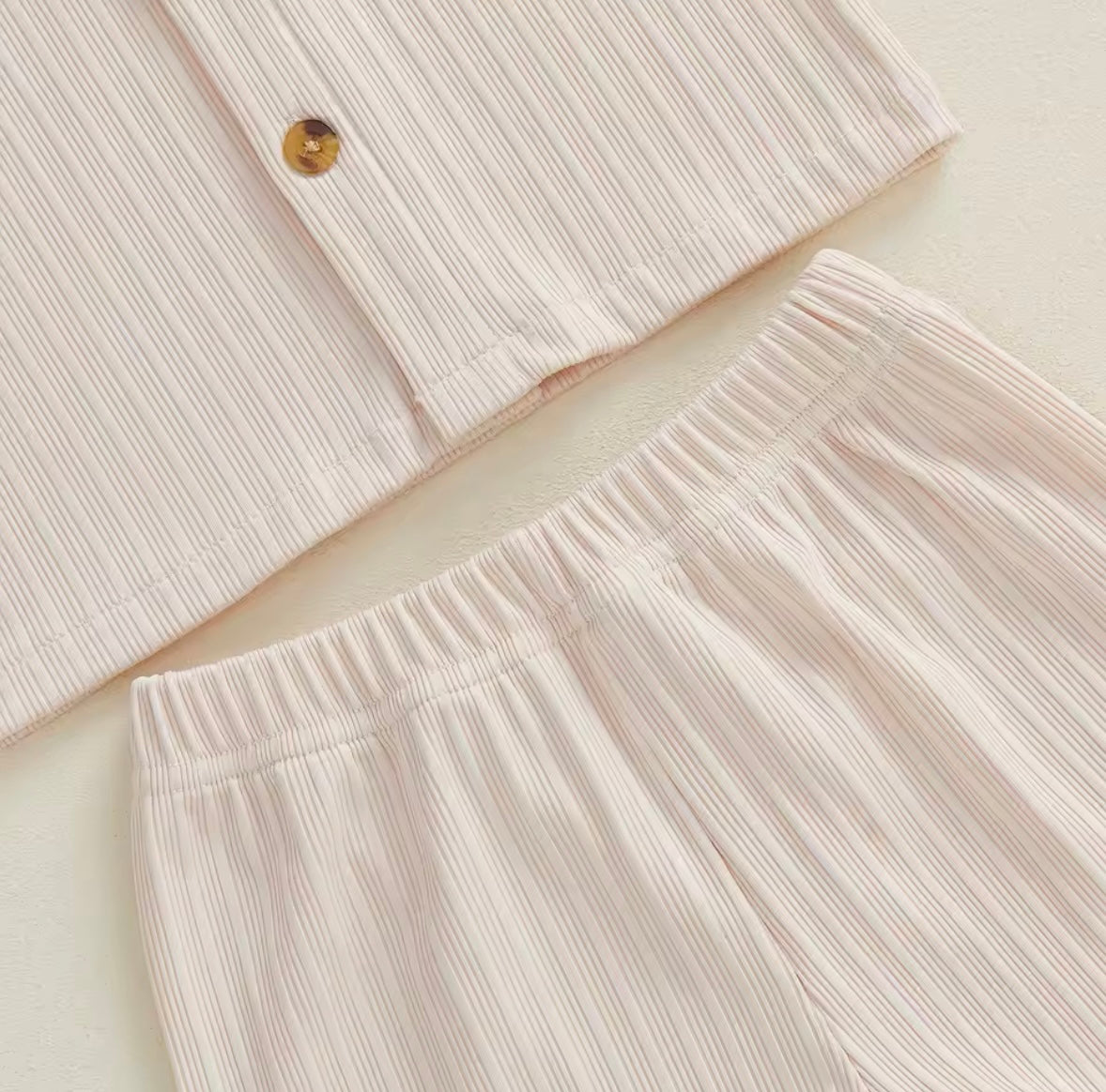 Close-up of a light pink textured shirt and pants on a beige background