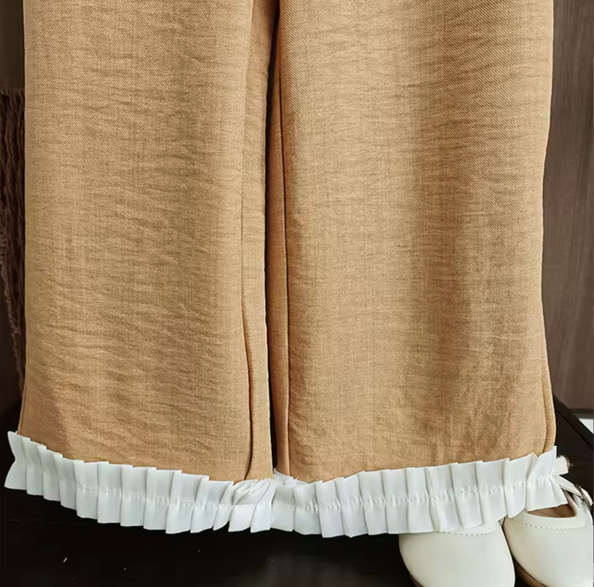 Brown pants with white ruffled hem on a mannequin.