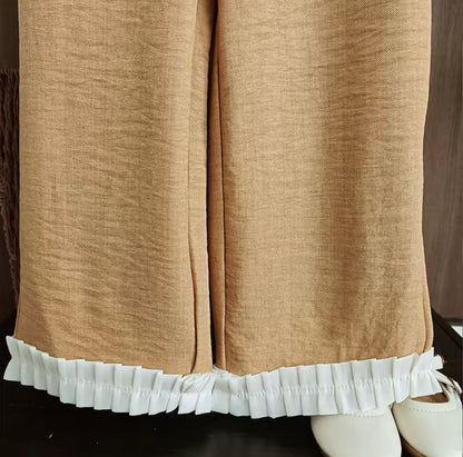 Brown pants with white ruffled hem on a mannequin.