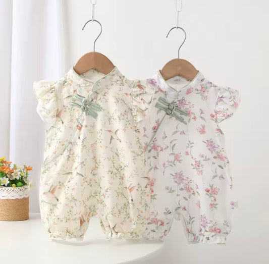 Two floral baby rompers on hangers against a white background