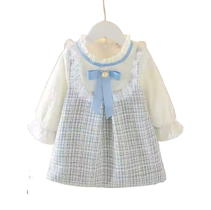 Children's dress with plaid skirt and white blouse on a hanger against a neutral background.