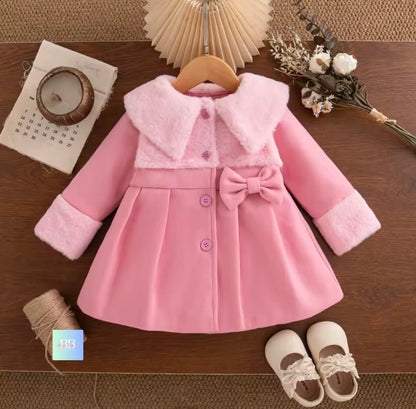 Pink children's coat with fur trim on a wooden surface, accompanied by shoes.