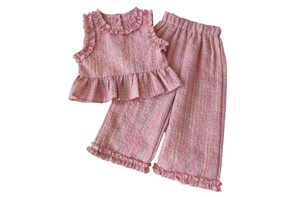 Pink ruffled outfit on a white surface with decorative items.