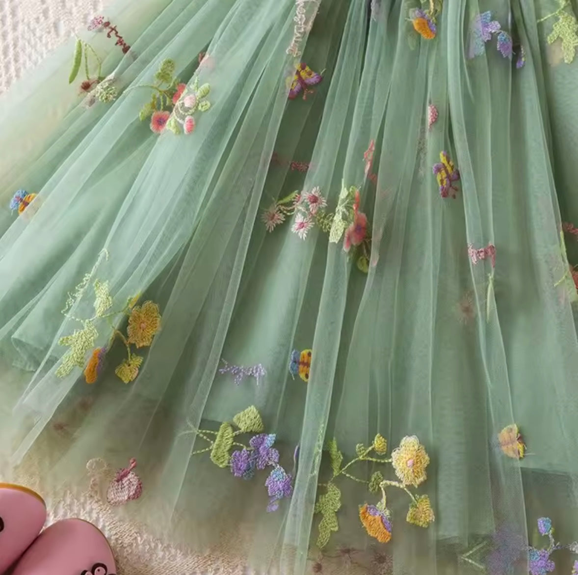 Green fabric with floral embroidery held by a person