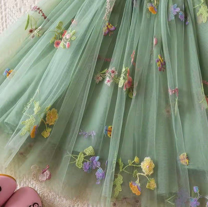 Green fabric with floral embroidery held by a person