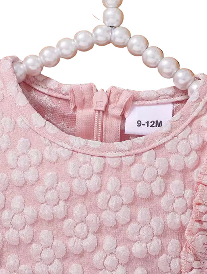 Pink textured dress with a pearl necklace and size label on a wicker surface