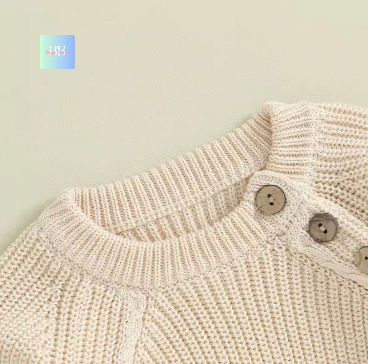 Close-up of a beige knitted garment with buttons on a light background