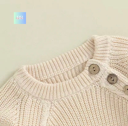 Close-up of a beige knitted garment with buttons on a light background