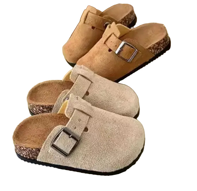 Pair of brown suede clogs with buckles on a light surface
