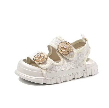 White sandal with gold floral embellishments on a white background