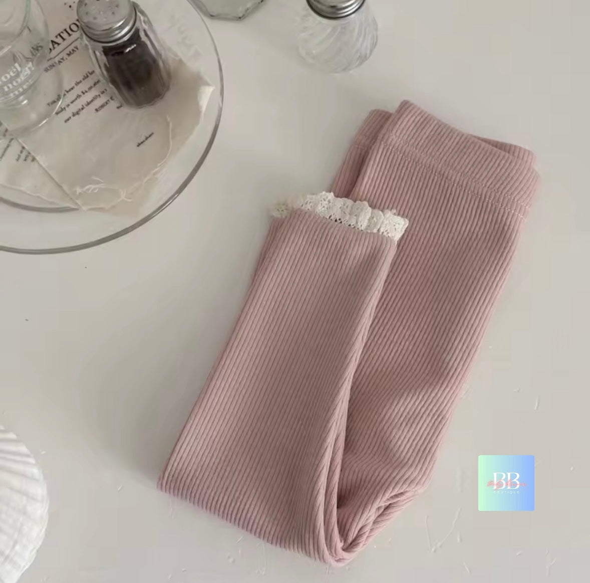 Folded ribbed leggings with lace trim on a light surface