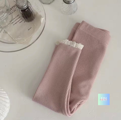 Folded ribbed leggings with lace trim on a light surface