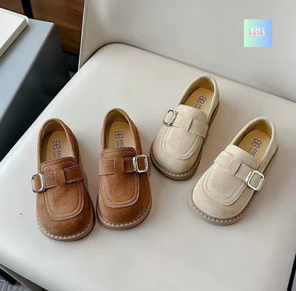 Pair of brown and beige children's shoes with buckles on a white surface.