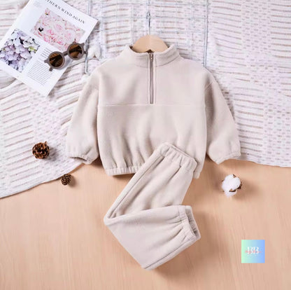 Children's beige fleece set on a wooden surface with a textured fabric background