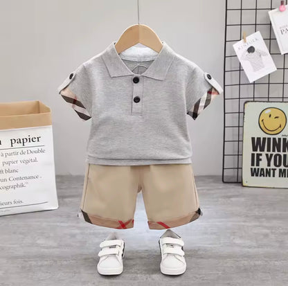 Children's outfit with gray polo shirt and beige shorts on a hanger against a neutral background.