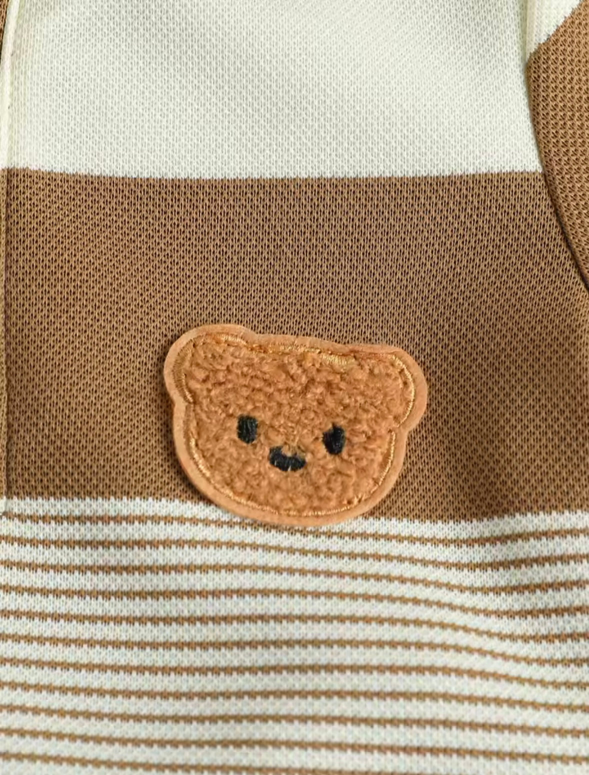 Close-up of a teddy bear face patch on a striped fabric background