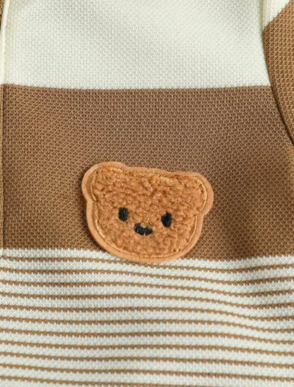 Close-up of a teddy bear face patch on a striped fabric background