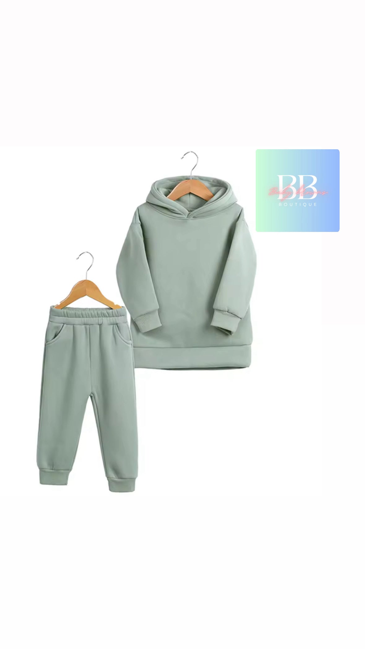 Children's green hoodie and jogger set on hangers with a brand logo in the corner.