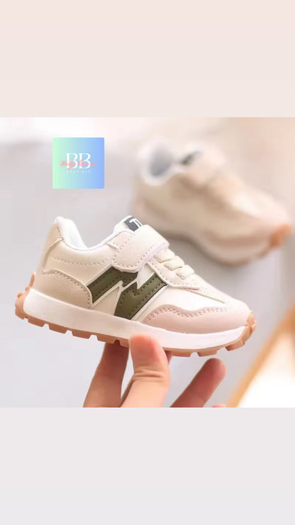 Baby pink and green sneakers held by a hand on a light gray background